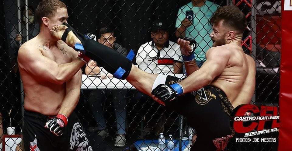 Rob landing a high kick on his opponent against the cage in a Castro Fight League MMA bout.