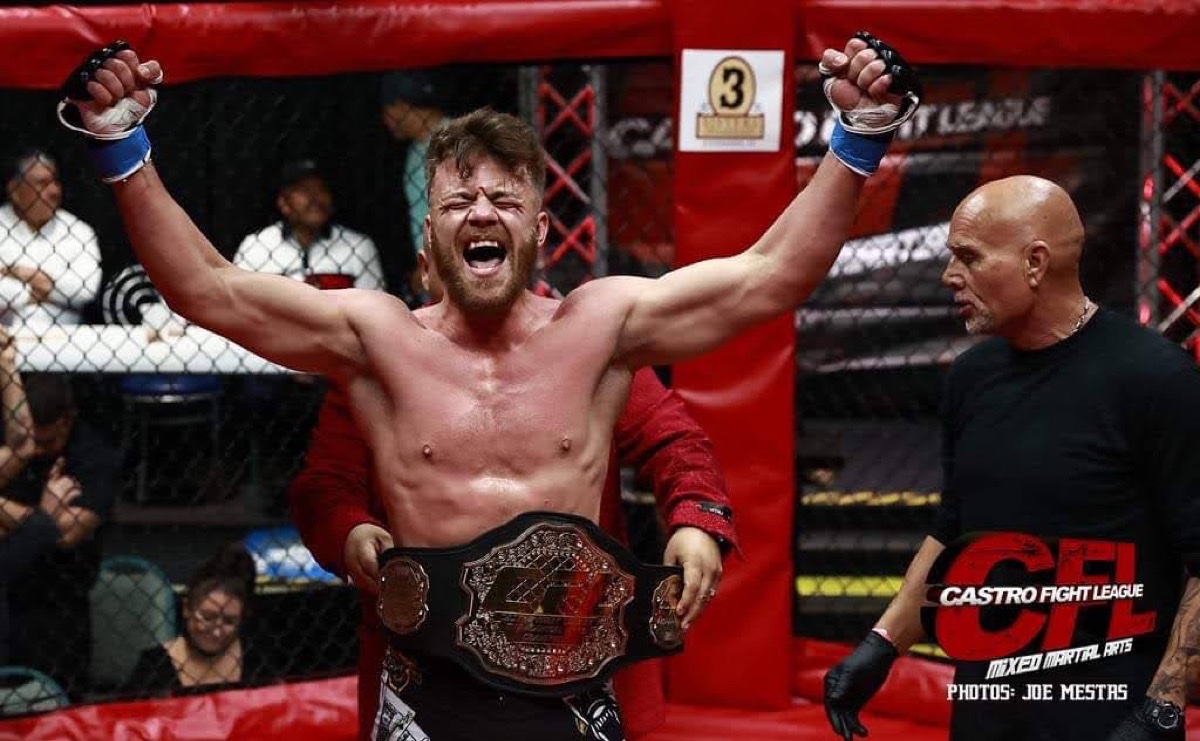 Rob inside the cage with the Castro Fight League championship belt, arms raised.